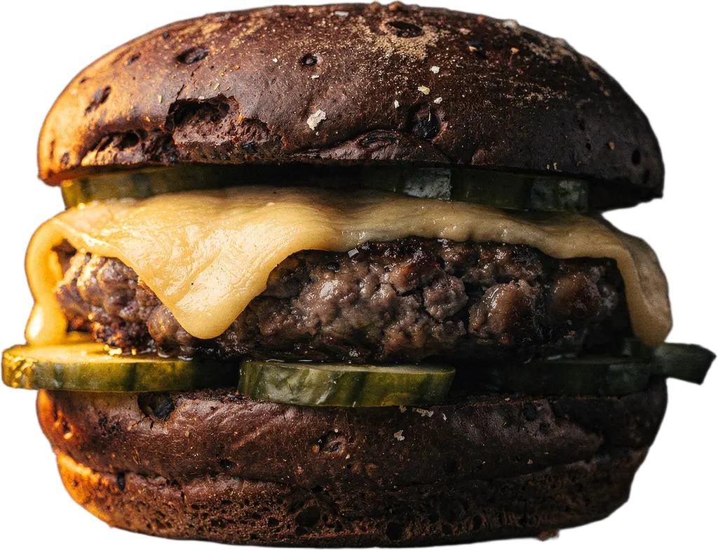 Ein Burger mit Raclette, eingelegter Gurke und scharfer Mayo auf Schwarzbrot-Bun
